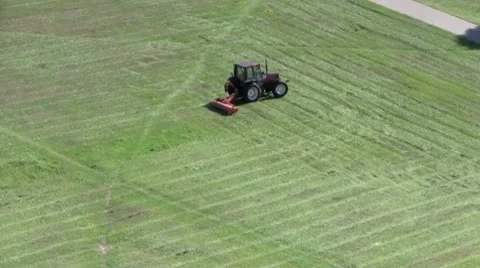 A mini tractor mows grass on a city meadow on a sunny summer day Stock Footage 10572854