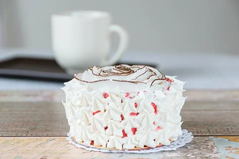 Mini vanilla cake decorated with dried coconut chips and whipped cream. In th Stock Photos