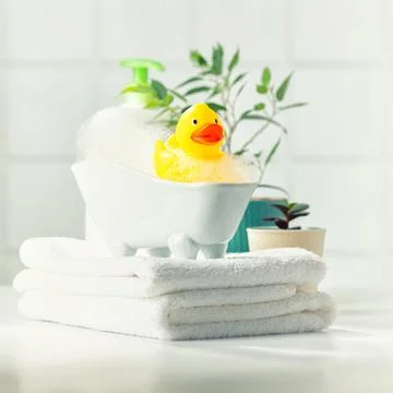 A miniature bubble bath, yellow rubber duck and white towels on bathroom co.. Stock Photos