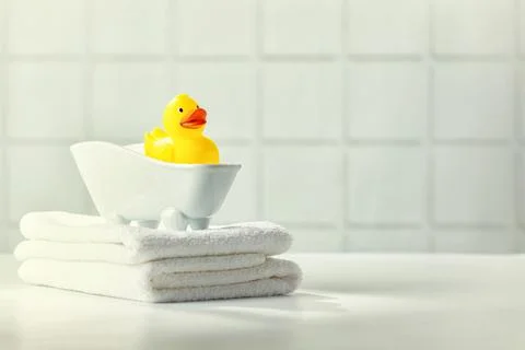 A miniature bubble bath, yellow rubber duck and white towels on bathroom co.. Stock Photos