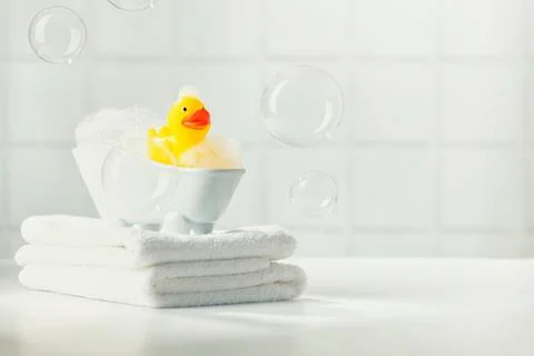 A miniature bubble bath, yellow rubber duck and white towels on bathroom co.. Stock Photos