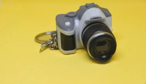 Miniature camera keychain on a yellow background, ideal for photography, ho.. Stock Photos