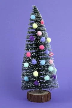 Miniature christmas tree decorated with mini garlands and pompoms as baubles Stock Photos