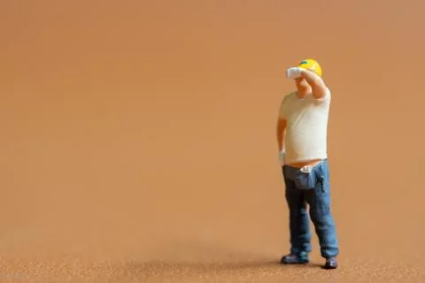 Miniature construction worker. He stands with one hand on his hip while wip.. Stock Photos