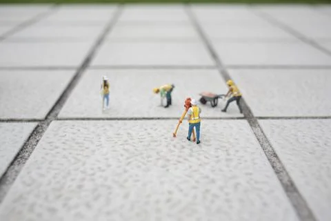 Miniature Construction Workers Collaborate On Large Tiled Surface Stock Photos