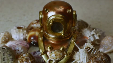 Miniature copper retro diving helmet surrounded by various beautiful sea shells Stock Footage 225808894