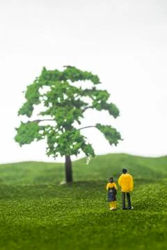 Miniature couple figures in front of a tree Stock Photos
