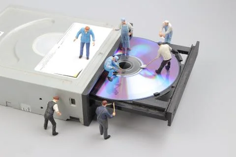 Miniature engineer and worker fixed to clean CD rom Stock Photos