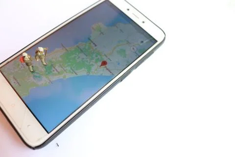 Miniature figure of an explorer posing on a digital map via a mobile phone Stock-Fotos