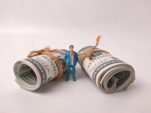 The miniature figure, standing between two large rolls of money Stock Photos