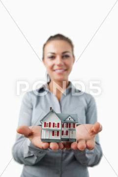 Miniature house being presented by young female estate agent Stock-Fotos