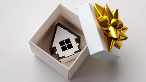 Miniature house in open gift box with a golden ribbon bow. Real estate concept. Stock Footage 325524183