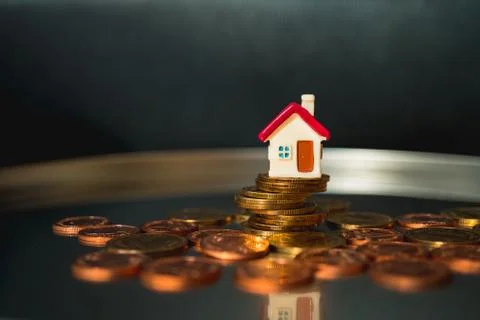 Miniature house on stack coins Stock Photos