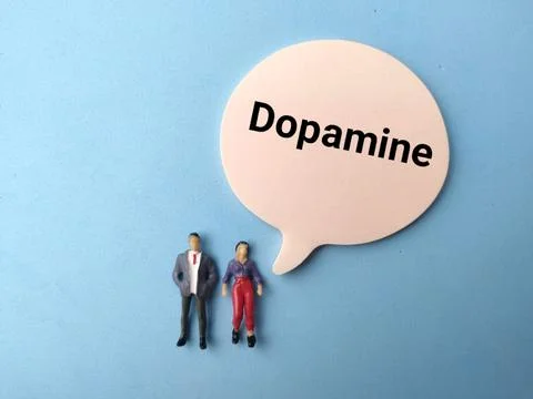 Miniature human figures standing next to a speech bubble labeled Dopamine o.. Stock Photos