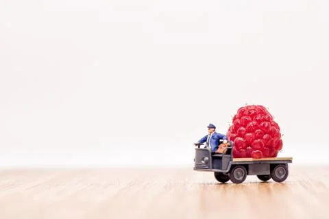Miniature lorry loaded with giant raspberry. Fruit delivery concept Stock Photos