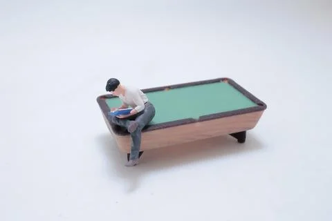 Miniature man reading on pool table Stock Photos