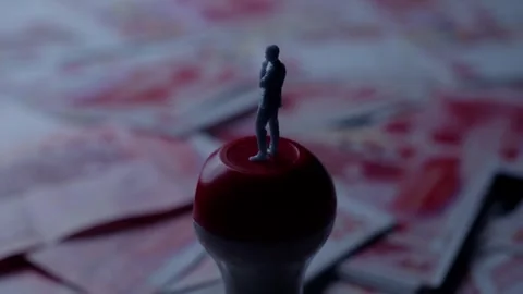 Miniature Man Standing on Red Stamp Top Over Blurred Money Background 動画素材 339068508