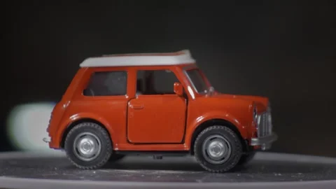 Miniature model car orange rotating on turntable closed door generic Stock Footage 337565391