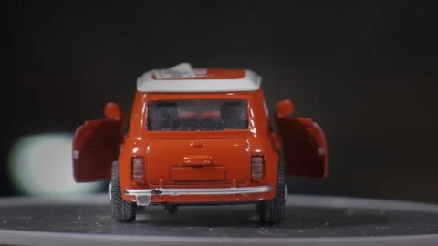 Miniature model car orange rotating on turntable open doors generic Stock Footage 337565500