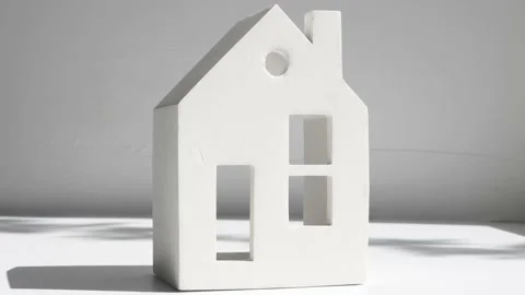 Miniature model of a house on a gray background with moving abstract shadows. Video stock 196114770