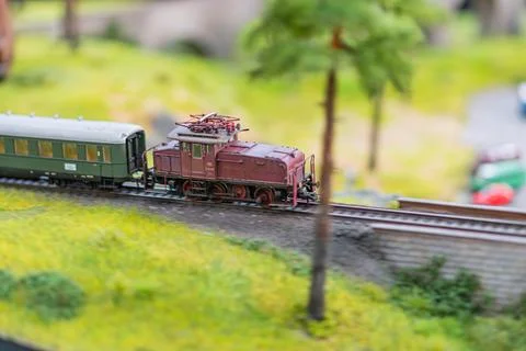 Miniature model train set in motion on winding tracks with a small bridge, .. Stock Photos