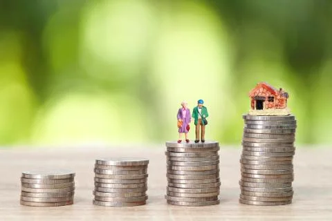 Miniature old couple standing on stack coins with house and green background Stock Photos