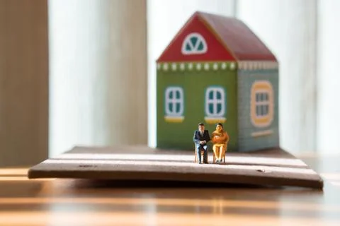 Miniature people, man and woman sitting in front of house Stock Photos