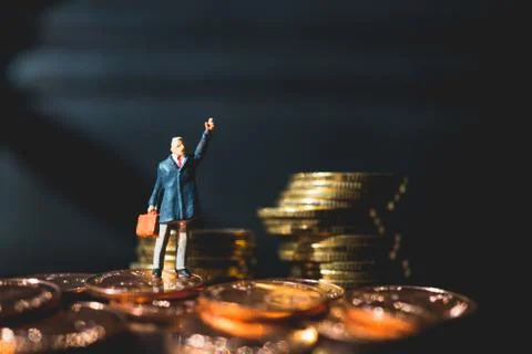 Miniature people, man standing on stack coins Stock Photos