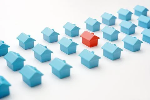 Miniature red model home different from group blue toy same type houses on wh Stock Photos