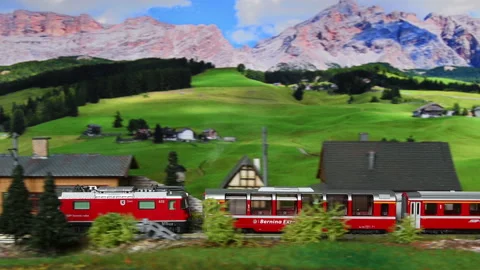 Miniature red train moving through a mountain environment. Stock Footage 236289823