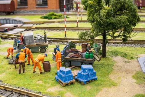 Miniature scene with tiny model construction workers in orange suits near a.. Stock Photos