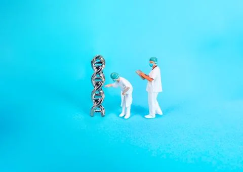 Miniature scientists analyzing DNA double helix model on blue background Stock Photos
