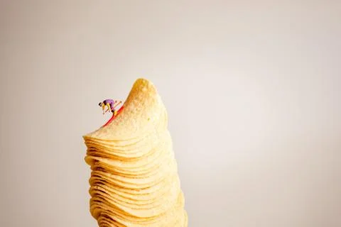 Miniature skier sliding down the stack of potato chips Stock Photos
