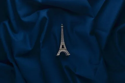 A miniature statuette of the Eiffel Tower on a dark blue cloth background. So Stock Photos