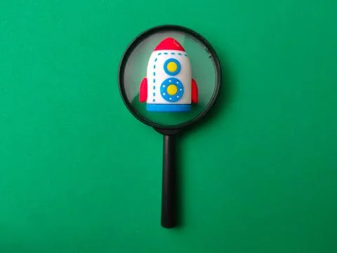 A miniature toy rocket viewed through a black magnifying glass centered on .. Stock Photos