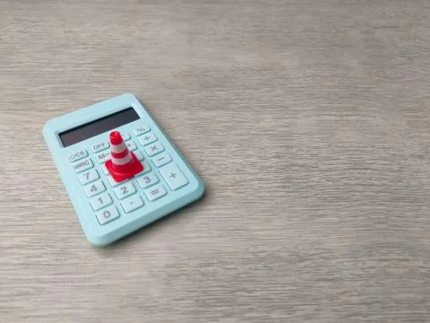 Miniature traffic cone placed on a light blue calculator Stock Photos