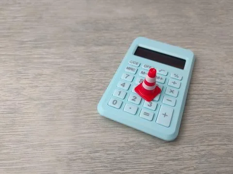 Miniature traffic cone placed on a light blue calculator Stock Photos