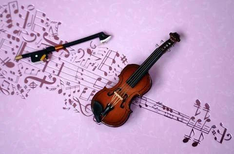 Miniature violin on a pink background with notes Stock Photos