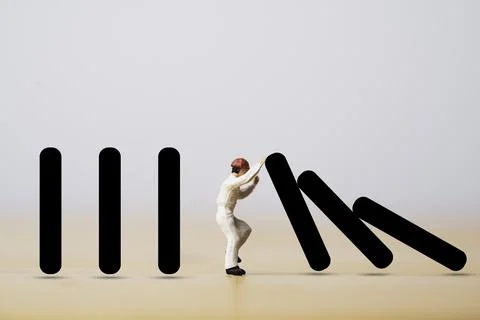 Miniature worker figure pushing rectangular bar which falling to prevent an.. Stock Photos