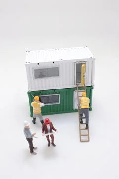Miniature workers assemble stacked modular container house model Stock Photos