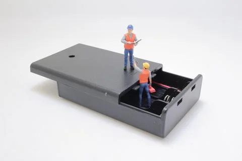 Miniature Workers Inspecting an Open Device Showing Inner Components Stock Photos