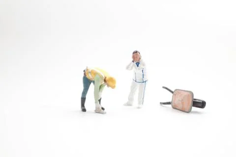 Miniature workers react beside fallen wheelbarrow on ground Foto stock