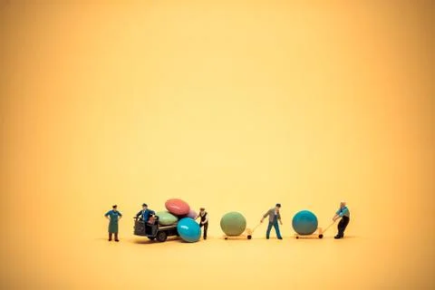 Miniature workers unloading sugar coated chocolate candies from truck Stock Photos