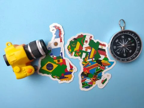 A miniature yellow camera, two map cutouts of Africa and South America, and.. Stock Photos