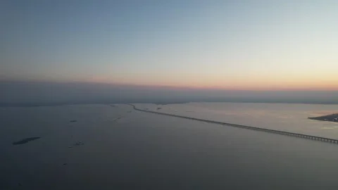 Minimal aerial view of long bridge across calm water at sunrise in China Stock Footage 337764924