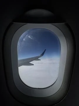 Minimal aircraft window view with wing silhouette over bright cloud ocean e.. Stock Photos