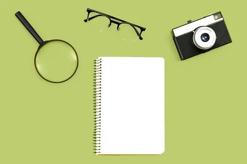 Minimal background with blank paper, camera, glasses, and magnifier, flat lay. Stock Photos