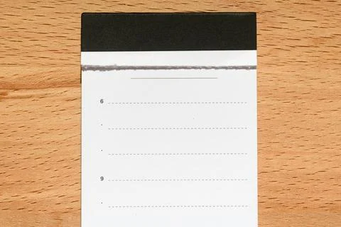Minimal blank notepad page with torn edge and black header lies on wooden des Stock Photos