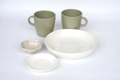 Minimal ceramic tableware set including two matte green mugs, white bowl, small  Stock Photos