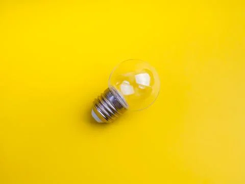 Minimal clear small round light bulb isolated on vibrant yellow background... 写真素材